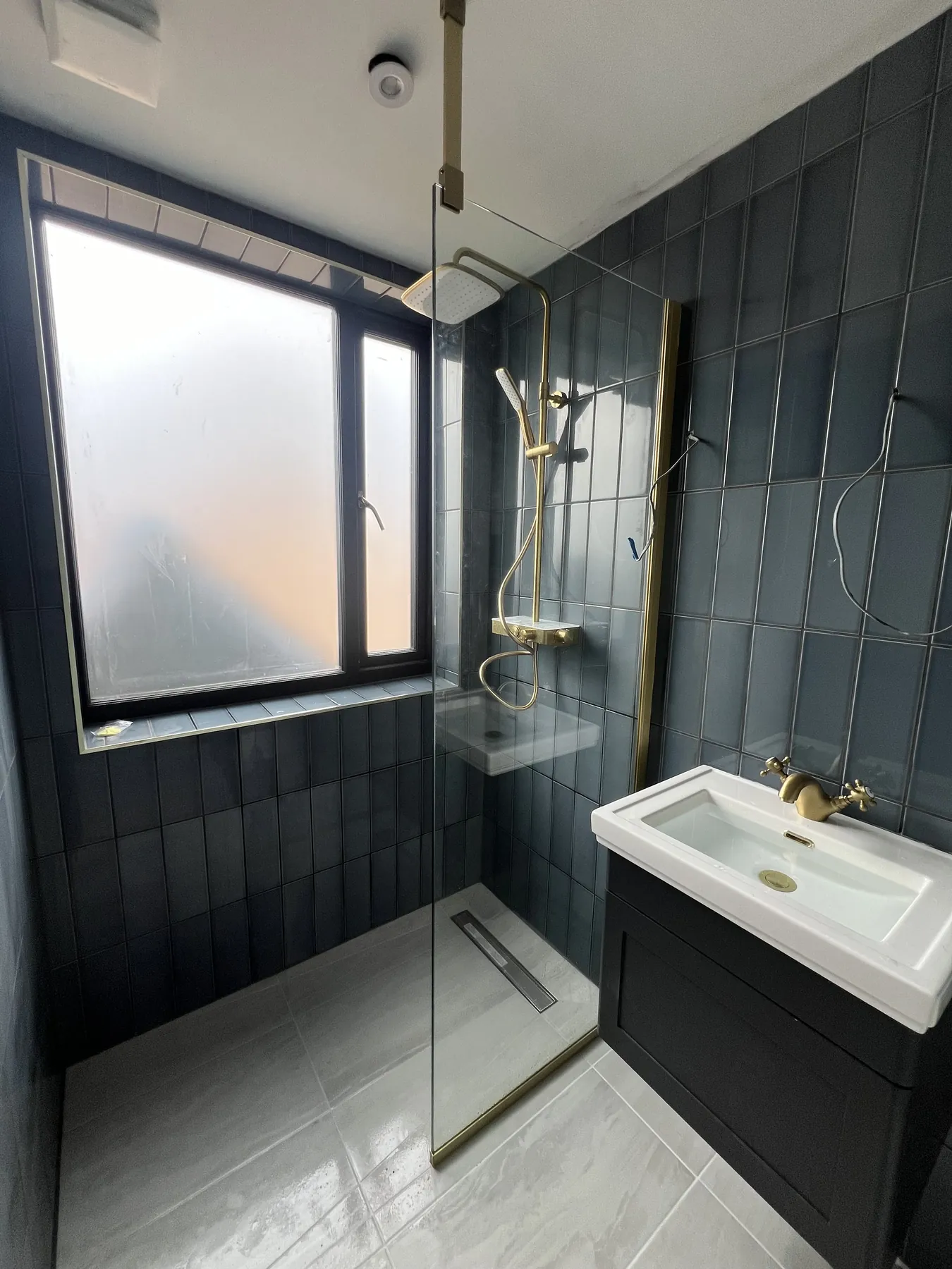 Completed dark tiled shower room with brass fittings