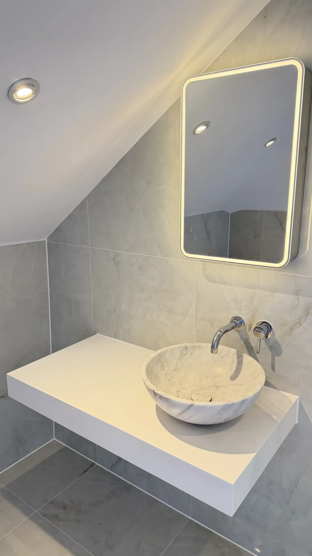 Marble basin and illuminated bathroom mirror